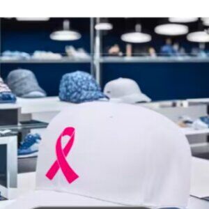 White cap with Breast Cancer logo (Ribbon) in bright red.